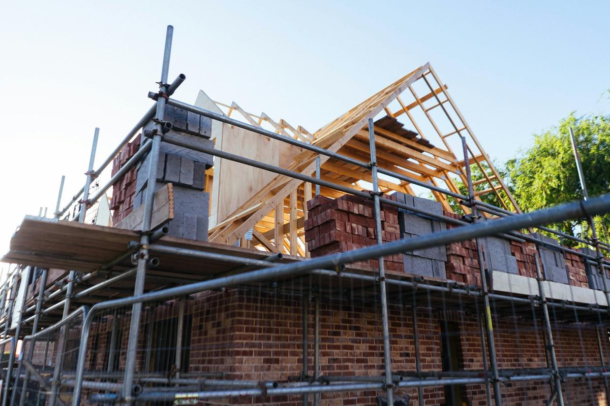 Bakstenen woning in aanbouw met stelling en een houten dakstructuur
